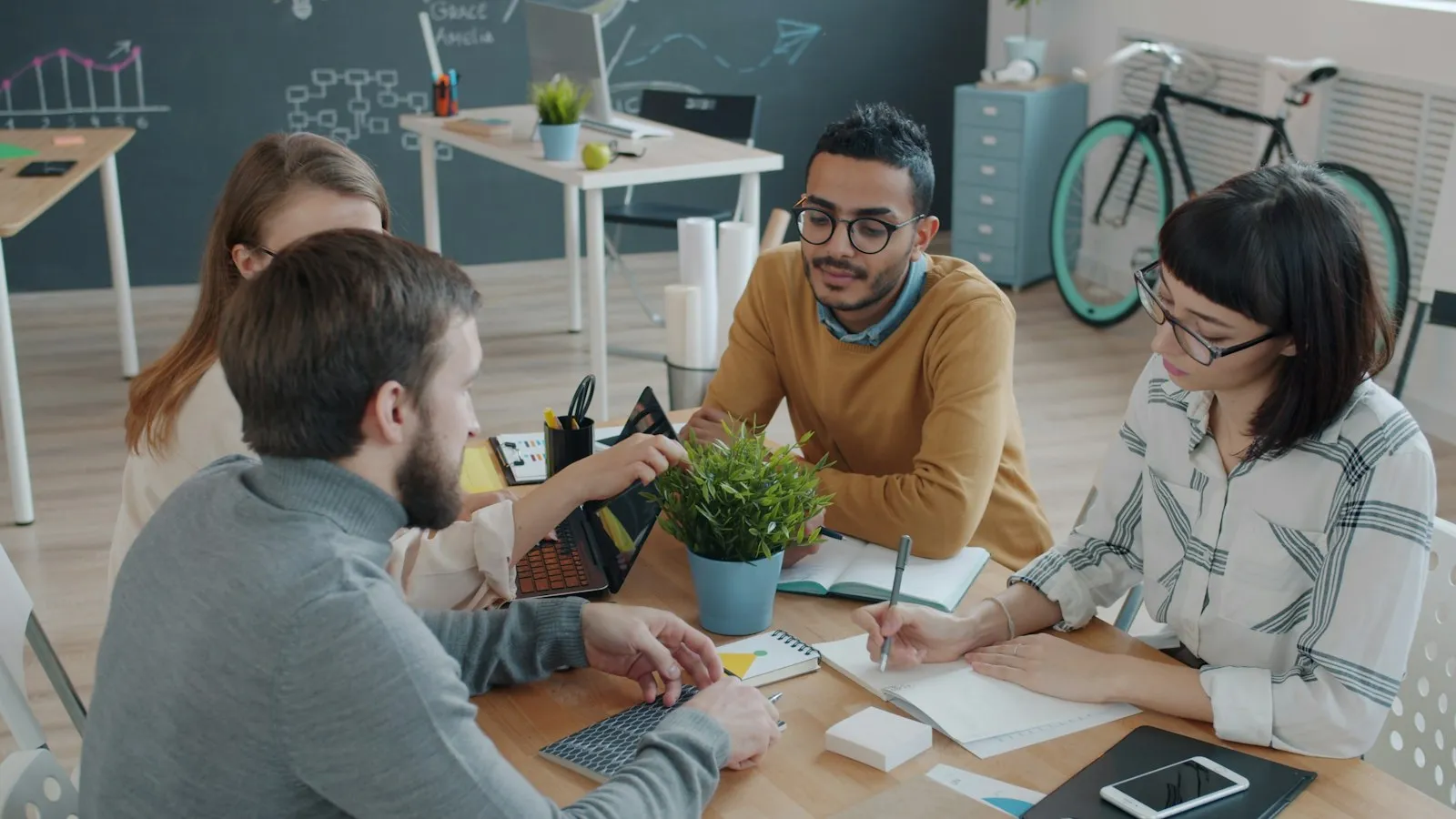 Equipo reunido alrededor de una mesa de trabajo, tomando notas